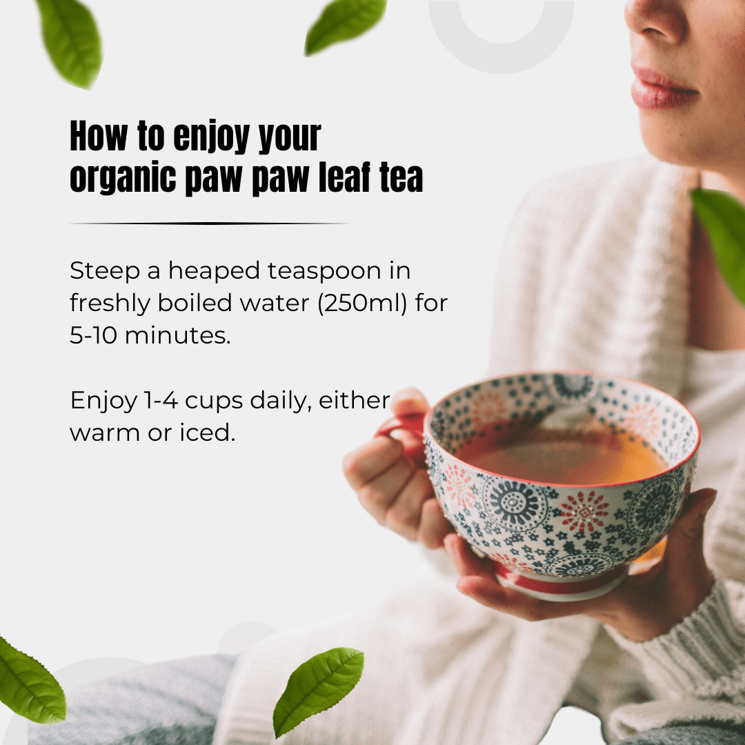 A person holds a Bondi Organic Paw Paw Leaf Tea cup by Bondi Beach Tea Co, known for aiding digestion. Steep 1 heaped tsp in 250ml freshly boiled water for 5-10 mins. Enjoy warm or iced, 1-4 times daily. Green leaves are nearby.