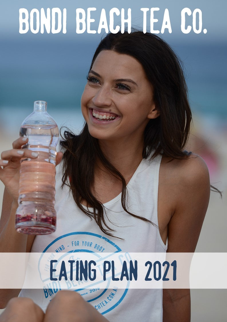 A woman smiles at the beach, holding a bottle filled with pink liquid. Shes wearing a white tank top with the Bondi Beach Tea Co. logo. The text reads: Bondi Beach Tea Co and FREE Eating Plan 2021, showcasing serenity and vitality against a sandy beach backdrop.