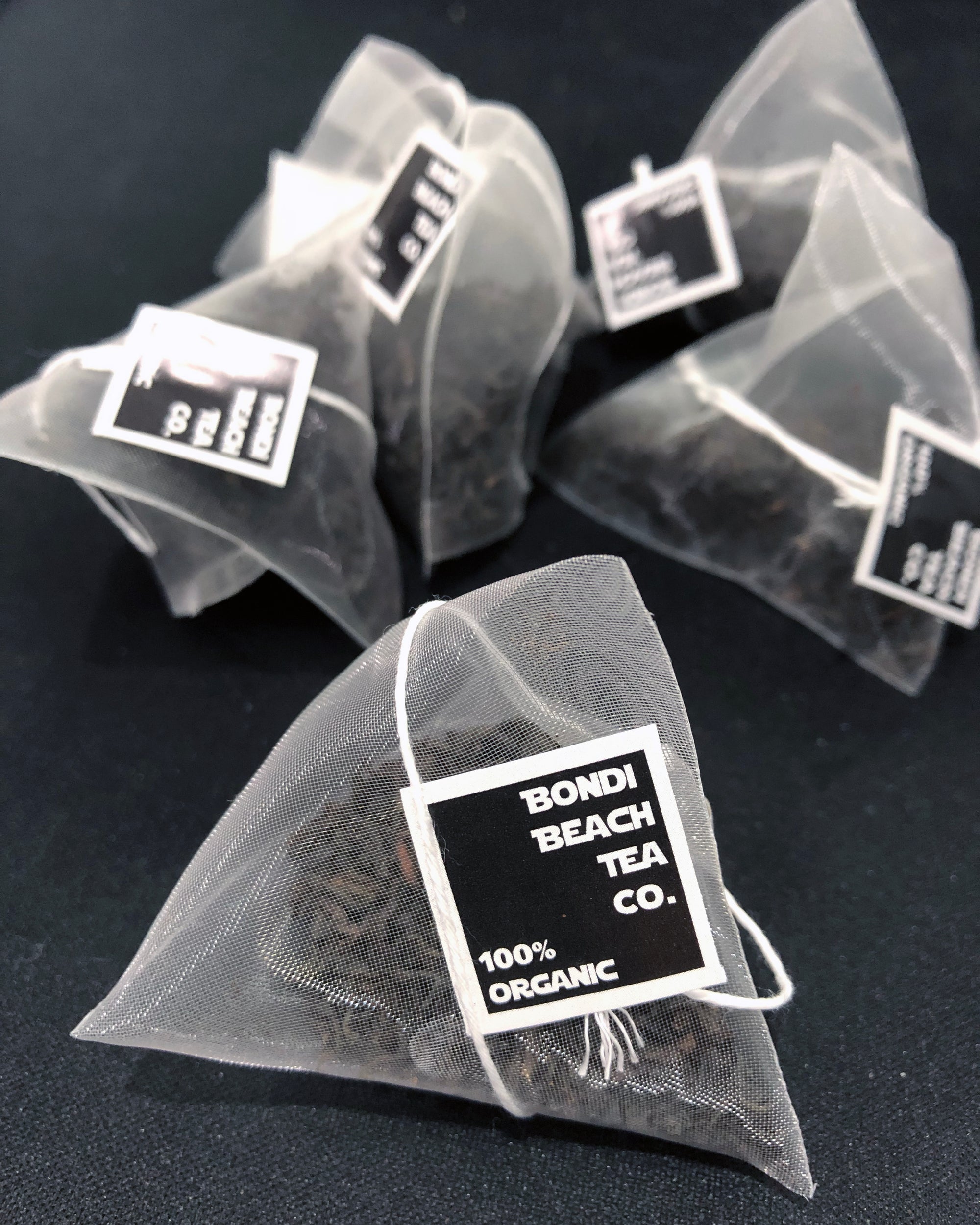 A vibrant mix of organic black tea leaves with small dried red, yellow, and blue flower petals embodies the floral flavor of Bondi Beach Tea Cos French Earl Grey Tea Blend on a white background.