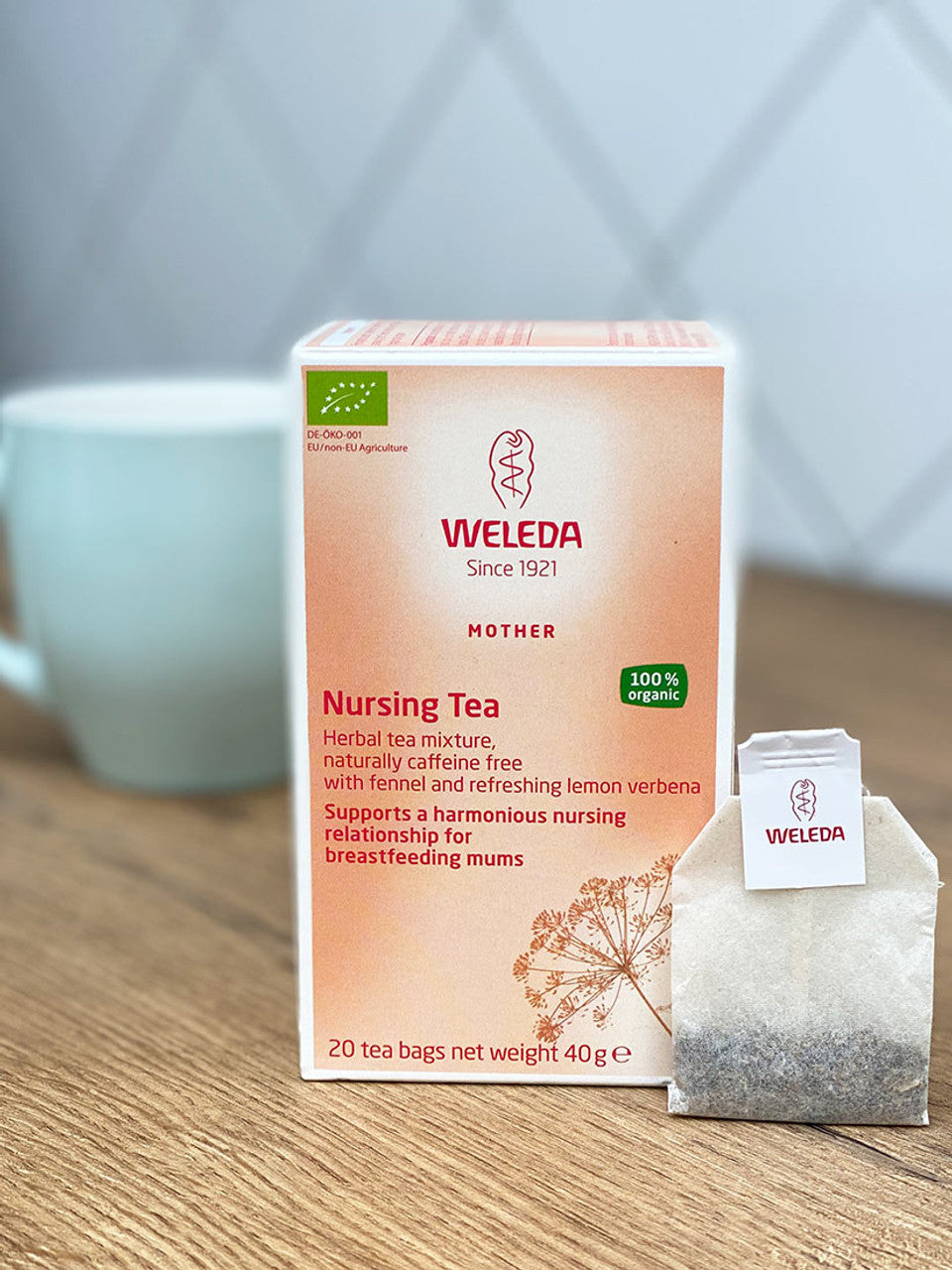 A box of Bondi Beach Tea Cos Weleda Nursing Tea - 20 Tea Bags sits with a tea bag and a blurred white mug, emphasizing its role in supporting a harmonious nursing relationship for breastfeeding mums.